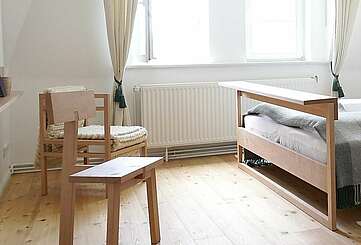 <p>Moderne Schlafzimmermöbel aus hellem Holz stehen in einem lichtdurchfluteten Zimmer. Cremefarbene Vorhänge und der Holzfußboden tragen zur Natürlichkeit bei.</p>