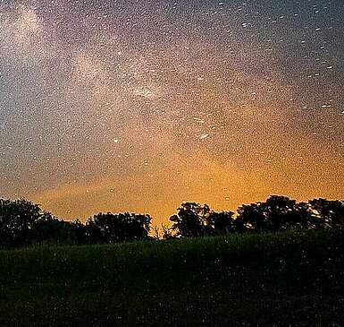 <p>Ein Mann steht bei Nacht auf dem Dach seines Wohnmobils und hält eine Taschenlampe in Richtung Himmel. Der Lichtstrahl ist vor der ebenfalls deutlich sichtbaren Milchstraße zu erkennen.</p>