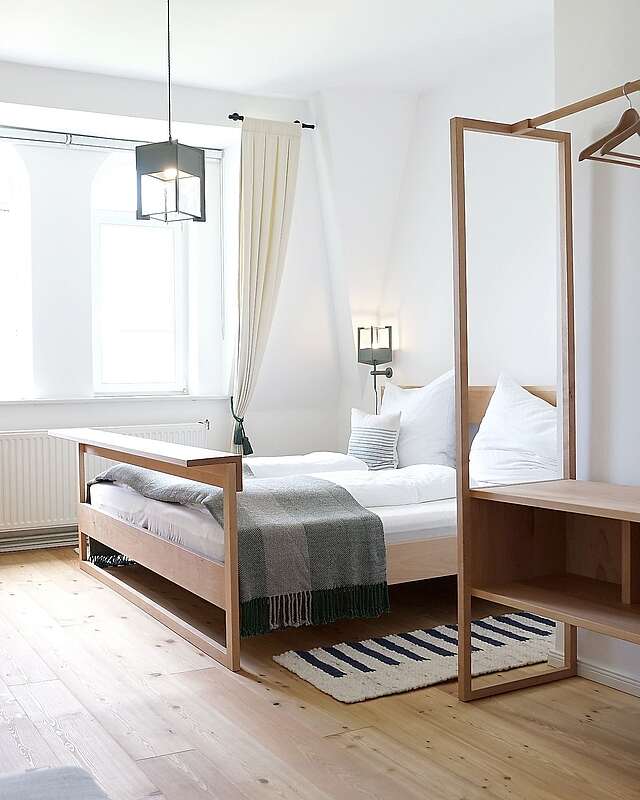 <p>Moderne Schlafzimmermöbel aus hellem Holz stehen in einem lichtdurchfluteten Zimmer. Cremefarbene Vorhänge und der Holzfußboden tragen zur Natürlichkeit bei.</p>