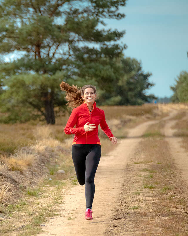 <p>Eine junge Frau joggt auf einem Sandweg durch die Kyritz-Ruppiner Heide</p>